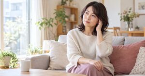 明るい部屋で座って耳に手を添える女性